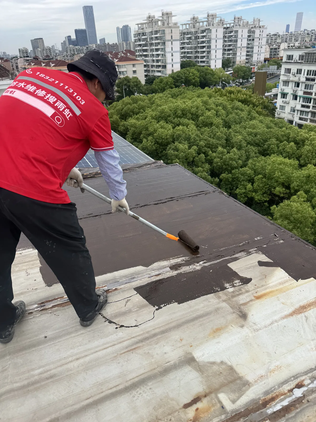 施工人员在屋面使用滚筒进行涂刷作业